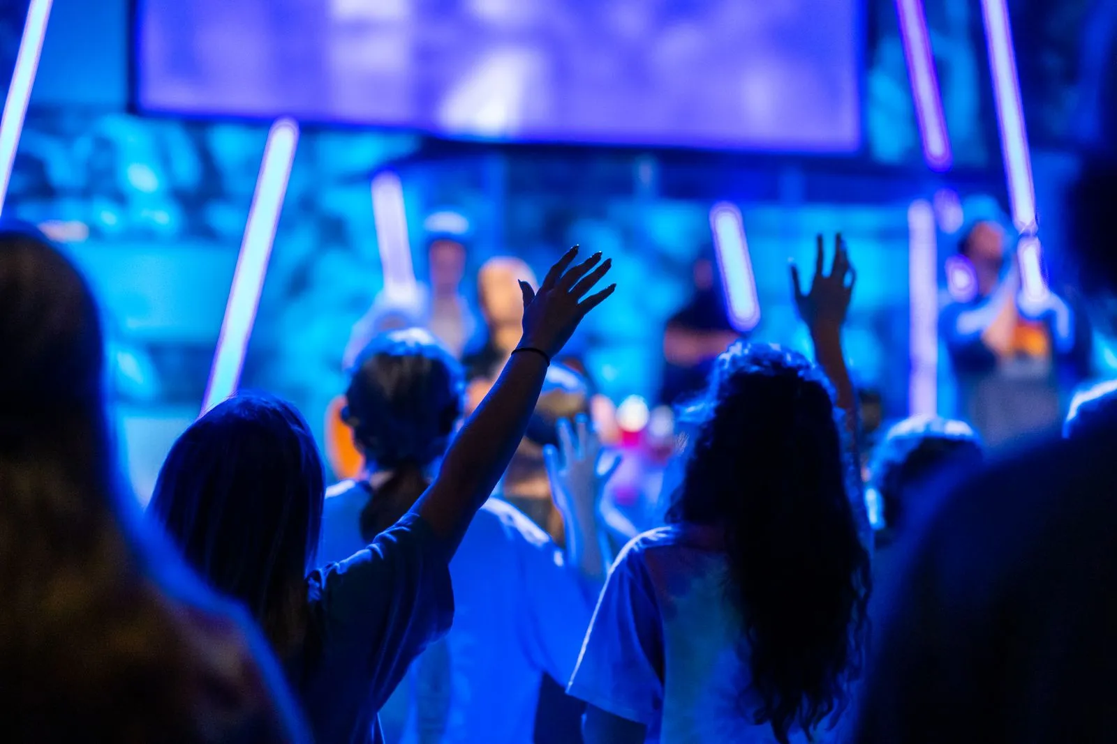 Hands up under violet stage lights