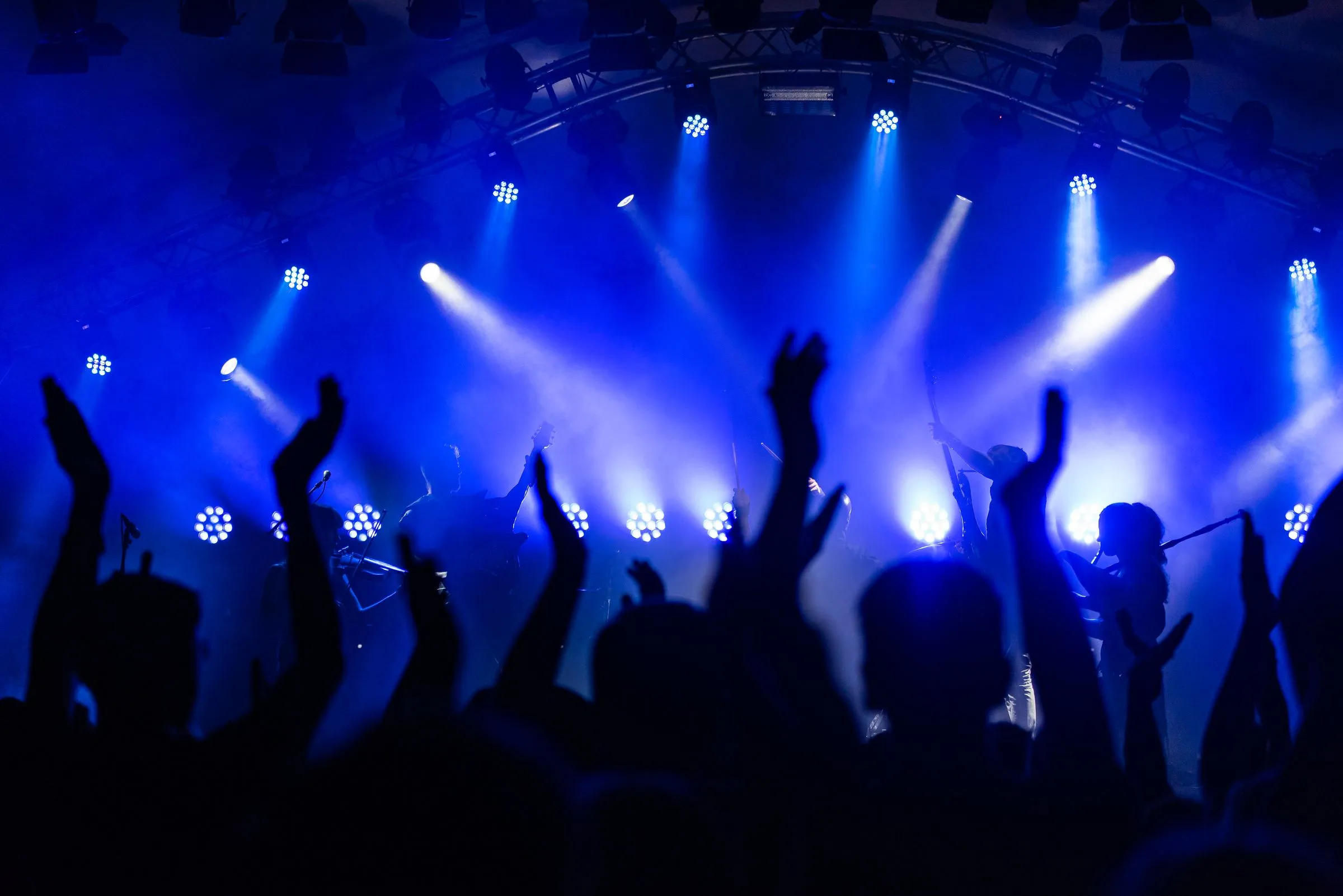 Crowd with hands up under blue stage lights